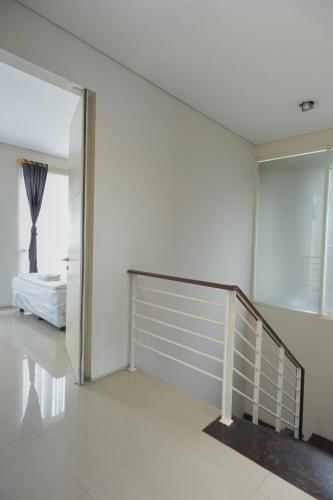 a white room with a staircase and a bed at GreenLake Vista in Surabaya