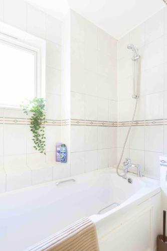 a white bathroom with a tub and a plant at Tower Bridge Home in London