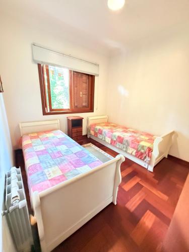 a bedroom with two beds and a window at Apartamentos Centrinho Capivari - Recanto Boticário in Campos do Jordão