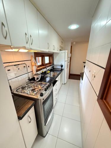 a kitchen with white cabinets and a stove top oven at Apartamentos Centrinho Capivari - Recanto Boticário in Campos do Jordão