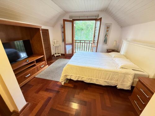 a bedroom with a bed and a flat screen tv at Apartamentos Centrinho Capivari - Recanto Boticário in Campos do Jordão