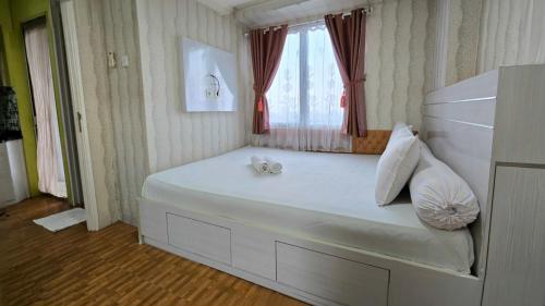 a bedroom with a large white bed with a window at BassuraCity Apartment near Hi-Speed Train Station -Min Stay 3 nights- in Jakarta