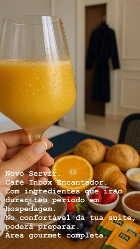 a person holding a glass of orange juice next to a table with donuts at Pousada Recanto da Família in Natal