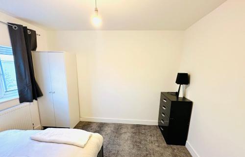 a bedroom with a bed and a dresser with a lamp at 224 Newcastle Street in Stoke on Trent