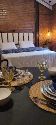 a table with plates and bowls on it with a bed at Pousada Chácara Kioski in Brotas