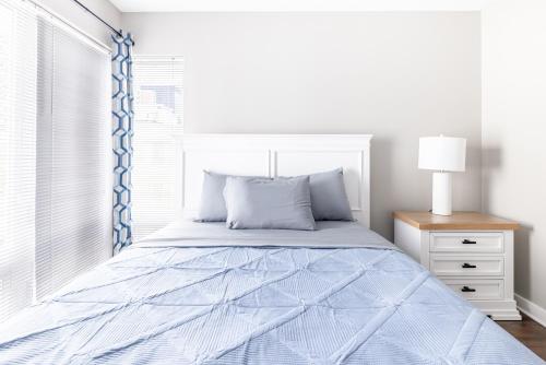 a bedroom with a bed with a blue comforter and a window at Luxury Downtown Townhome Private Garage Unit 3 in Cleveland