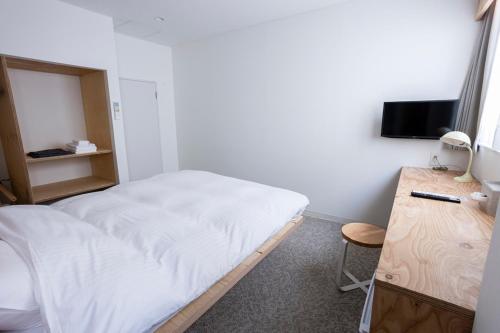 a bedroom with a bed and a desk and a television at イリゴアパートメントホテル in Hirosaki