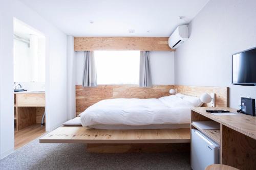a bedroom with a bed and a desk and a television at イリゴアパートメントホテル in Hirosaki