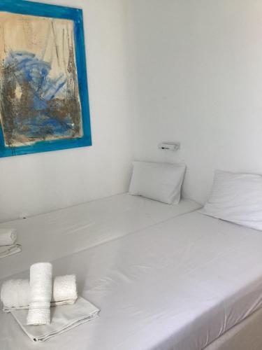 a white bed with two pillows and a painting on the wall at Windmill Rooms in Antiparos Town