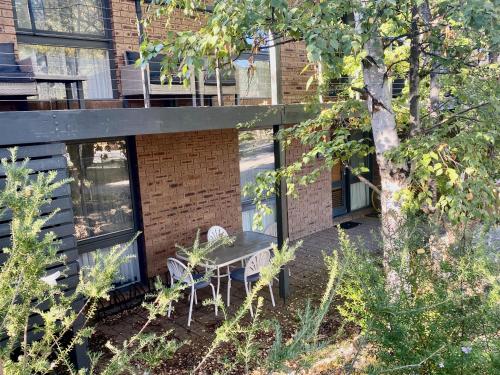 a patio with a table and chairs in front of a building at Aalen in Jindabyne