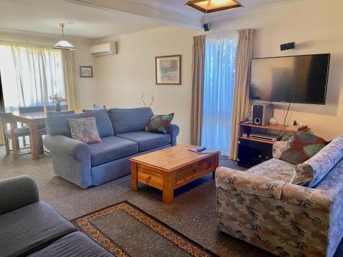 a living room with two couches and a flat screen tv at Aalen in Jindabyne