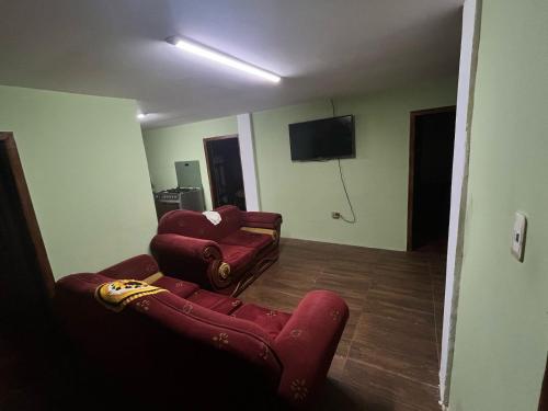 a living room with two red chairs and a television at Lugar tranquilo in Pititic