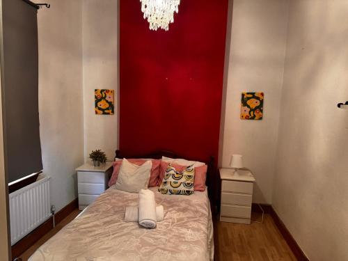 a bedroom with a bed with a red wall at 7 Bedroom Cosy Walsall Stay - WiFi & Free Parking in Walsall