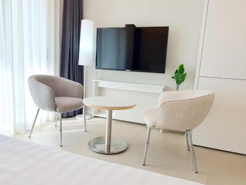 a hotel room with two chairs and a table and a tv at Le Bleu Naksan by Orot in Yangyang