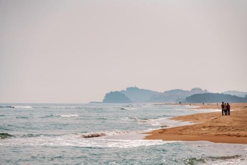 a group of people walking on the beach at Le Bleu Naksan by Orot in Yangyang