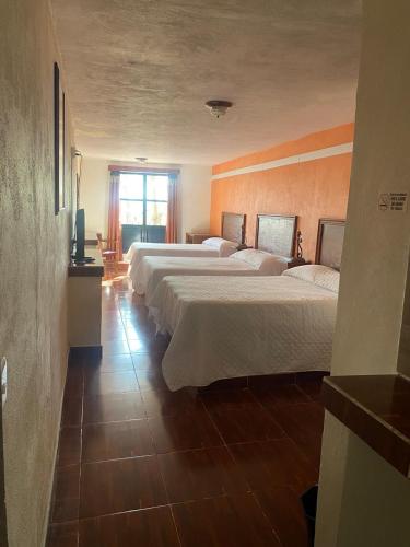 a hotel room with three beds and a window at Casa 12 Reales in Guanajuato