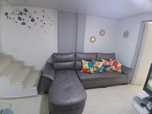 a living room with a brown leather couch and stairs at Acogedor apartamento en Pereira in Pereira