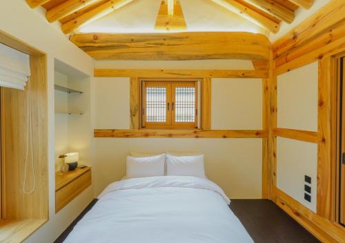 a bedroom with a large white bed in a room with wooden ceilings at Hanok stay Jungwooga in Gyeongju