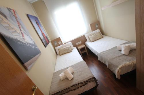 um pequeno quarto com 2 camas e uma janela em ACP Cambrils Puerto Apartamentos em Cambrils