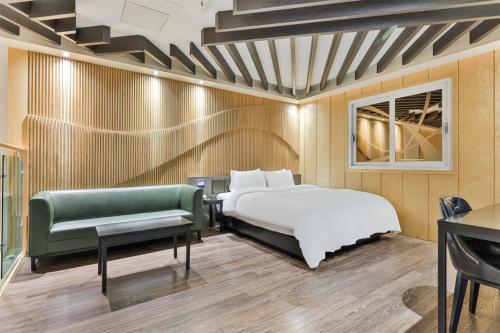 a bedroom with a bed and a green couch at 포항 에이원 호텔 죽도 Pohang A1 Jukdo in Pohang