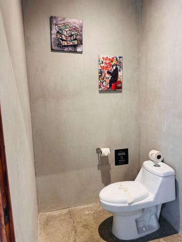 a bathroom with a toilet and two pictures on the wall at Villa Mary in Punta Leona