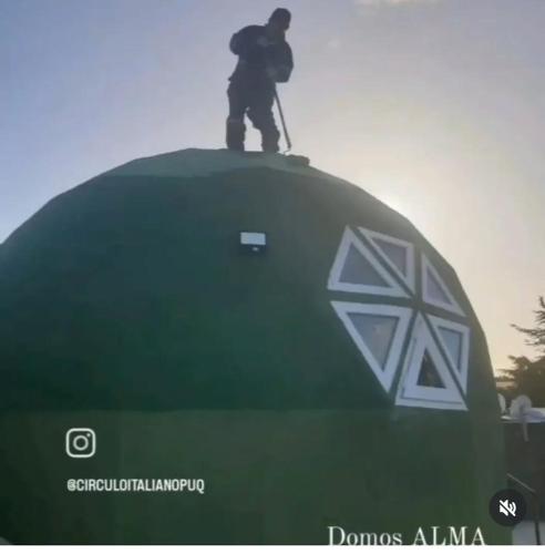 a man is standing on top of a green dome at Excelente domo in Punta Arenas