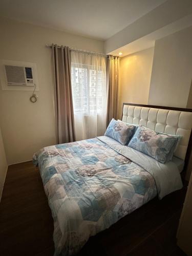 a bedroom with a bed with a comforter and a window at Condo in Davao City in Davao City