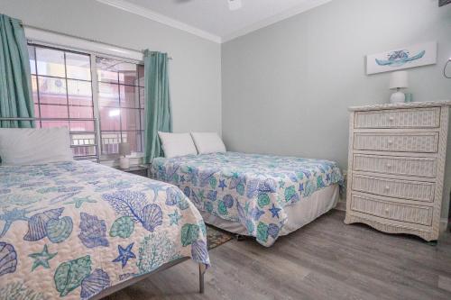 a bedroom with two beds and a dresser and a window at Spacious 3-Bedroom Condo at Sunset Bay Perfect for Families in Ocean City in Ocean City