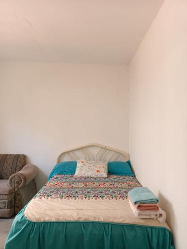 Bett in einem Zimmer mit Stuhl in der Unterkunft Casa Tobe in Puerto Escondido