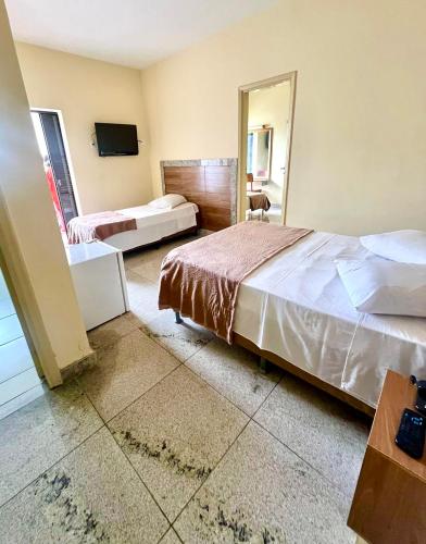 a hotel room with two beds and a mirror at Alvorada Palace Hotel de Poços in Poços de Caldas