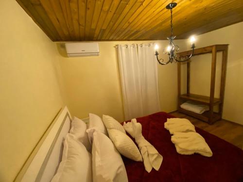 a bedroom with a bed with white pillows and a chandelier at Chales Gramado Exclusive in Gramado