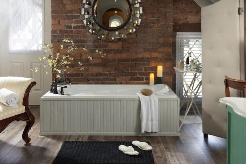 a bathroom with a bath tub and a brick wall at Inn at Woodhaven-In the Heart of the Bourbon Trail-Over 12 Distilleries Nearby in Louisville