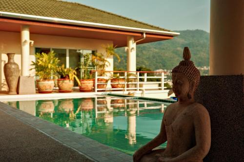 a statue of a woman sitting next to a swimming pool at Over the Moon villa in Patong Beach