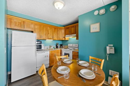 a kitchen with a wooden table and a white refrigerator at Royal Kuhio 2309 - Spacious Studio with Stunning Ocean Views in the Heart of Waikiki! in Honolulu
