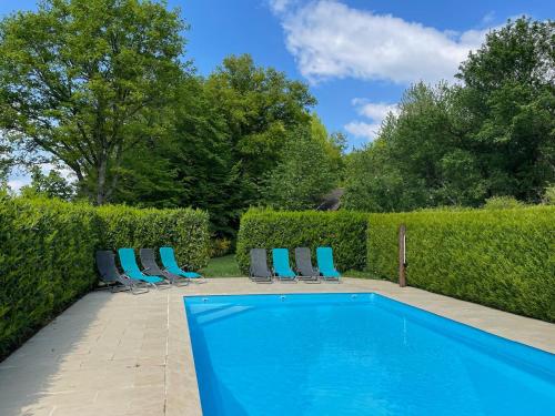 - une piscine avec des chaises bleues et une haie dans l'établissement Domaine des Volets Jaunes familial avec piscine chauffée - FR-1-586-56, à Préveranges