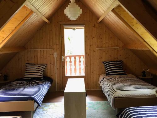 deux lits dans une chambre mansardée avec une fenêtre dans l'établissement Domaine des Volets Jaunes familial avec piscine chauffée - FR-1-586-56, à Préveranges