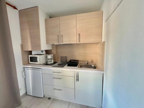 une petite cuisine avec des armoires blanches et un évier dans l'établissement Studio cabine 4 pers avec piscine à La Grande Motte - FR-1-716-84, à La Grande Motte