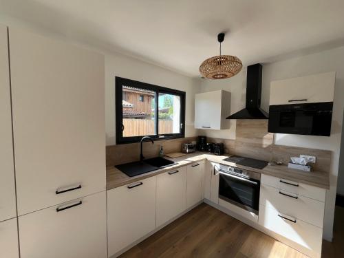une cuisine avec des armoires blanches et une fenêtre dans l'établissement Maison T4 à La Teste-de-Buch avec Terrasse et WIFI - FR-1-319-603, à La Teste-de-Buch