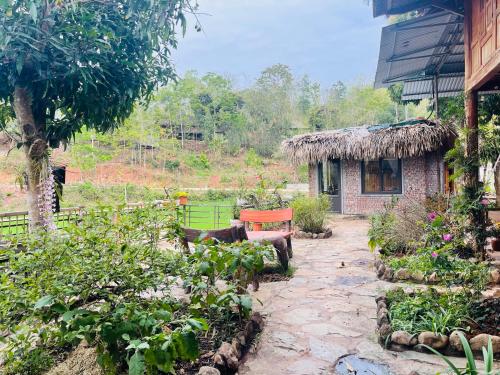 a garden with a bench and a small building at Quế Homestay in Hòa Bình