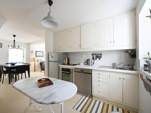 une cuisine avec des armoires blanches et une table à l'intérieur dans l'établissement Maison de village charme central île - FR-1-434-121, aux Portes