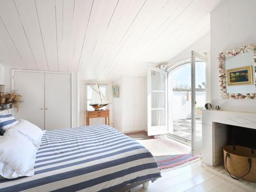 a white bedroom with a bed and a fireplace at Maison de village charme central île - FR-1-434-121 in Les Portes