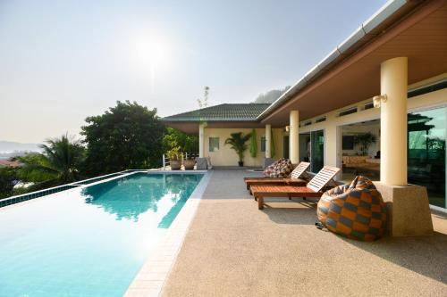 a swimming pool with two benches and a house at Over the Moon villa in Patong Beach