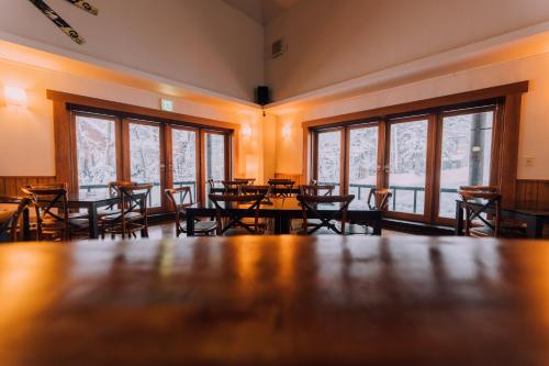 a dining room with tables and chairs and windows at Double Black Hotel in Hakuba