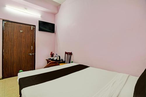 a bedroom with a white bed and a wooden door at Hotel O Mahalaxmi lodge in Cuttack