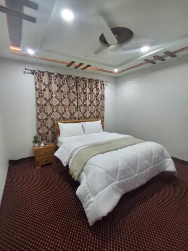 a bedroom with a large white bed and a ceiling at North Travelicious Guest Room Near Skardu Airport in Skardu