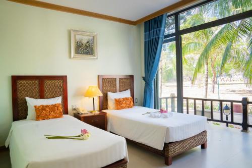 two beds in a room with a window at Lotus Vung Tau Resort & Spa in Vung Tau