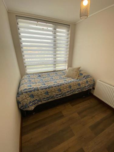 a small bed in a room with a window at Amplio,centrico y bello in Puerto Varas