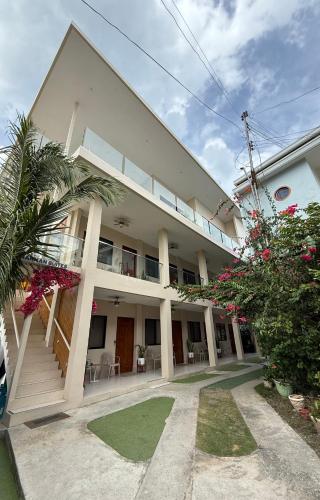 a large white building with a balcony and some plants at HARMAN SUITES Moalboal in Moalboal