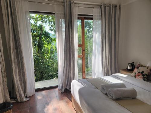 a bedroom with a bed and a large window at Miknaon Farmstay in Pedong