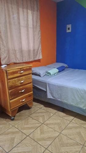 a bedroom with two beds and a dresser and a window at Hostal Niña Oly in Tamanique